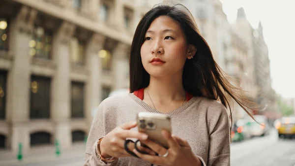 亚洲长发女孩的画像 看上去很沉思 穿着休闲的衣服 和朋友们在街上聊天 在户外使用手机的年轻妇女 — 图库照片