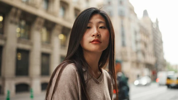 Attractive Asian long haired woman standing on the street and looking at camera. Asian girl walking in downtown alone
