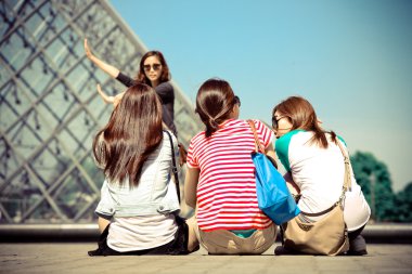 Üç kız louvre piramit paris üzerinde oturmak.