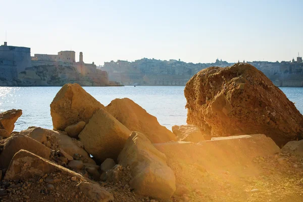 Olhar para a cidade através de grandes pedras, Malta — Fotografia de Stock