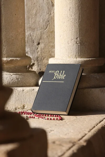 Bible and rosary on a wall. — Stock Photo, Image