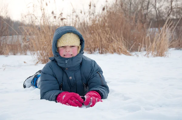 Retrato de menino feliz jaz na neve — Fotografia de Stock