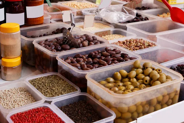 Pickled olives and nuts snacks inside plastic containers sold on market