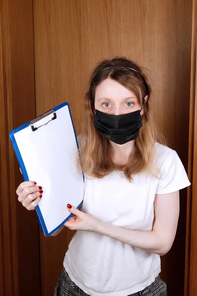 若いです女性身に着けていますウイルス保護医療面マスク保持空のホワイトペーパー上クリップボード — ストック写真