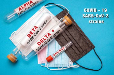 Laboratuvarda test edilen farklı SARS-CoV-2 virüslerinin test tüpleriyle tıbbi maske yığını.