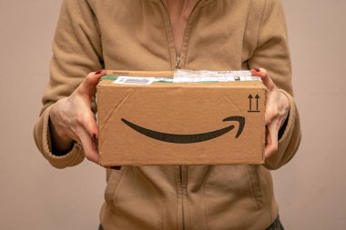 Londra, Birleşik Krallık - 10 Aralık 2021: Paket Amazon 'dan evine teslim edildikten sonra elinde kapalı karton paket tutan kadın.