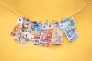 Banknotes of different international currencies hanging on a string