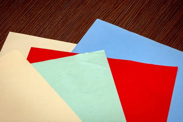 五颜六色的彩色纸堆在木制背景桌子上 — 图库照片