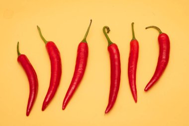 Sarı arka planda izole edilmiş kırmızı acı biber sırası.