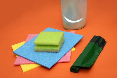 Turuncu arka planda ev temizlik aletleri ve ekipman yığını