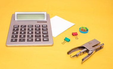 Metal zımba ve ataç ofis kağıtlarıyla modern elektronik hesap makinesi.