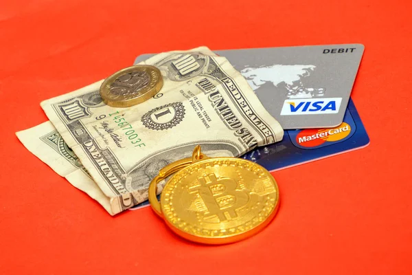 Londra, Birleşik Krallık - 27 Mayıs 2022: Kırmızı arka plandaki ödemeler için dolar kağıt faturası ve kredi kartlarıyla birlikte altın bitcoin kripto para birimi.