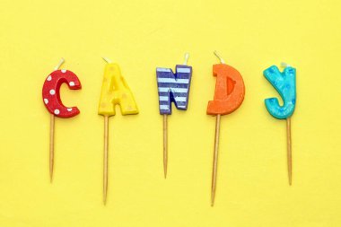 Sarı arkaplanda izole edilmiş renkli mumlar.