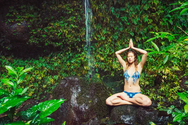 Mulher fazendo Yoga perto de cachoeira tropical — Fotografia de Stock