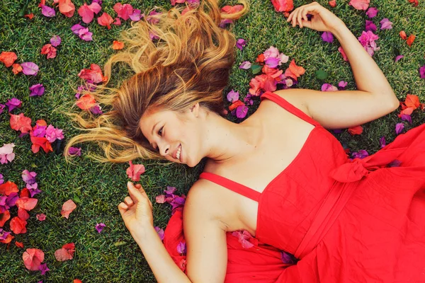 Schöne junge Frau, die in Blumen liegt — Stockfoto