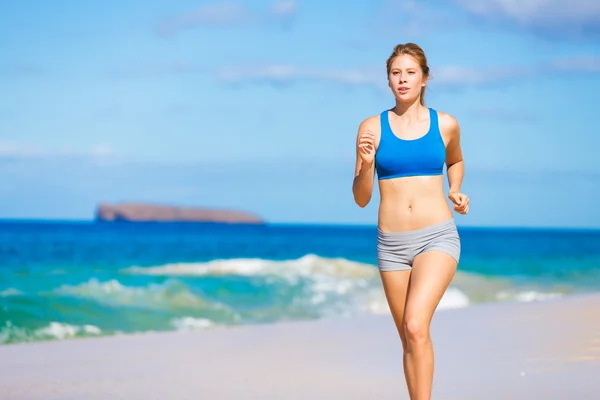 Schöne athletische Frau läuft am Strand Stockbild
