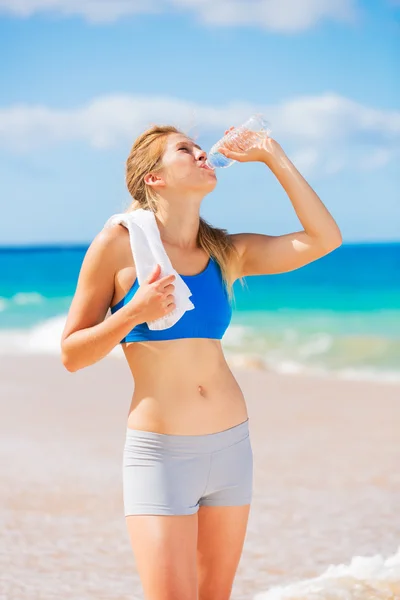 Hermosa joven agua potable después del entrenamiento en la playa — Foto de Stock