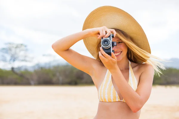 Krásná žena na pláži s fotoaparátem — Stock fotografie