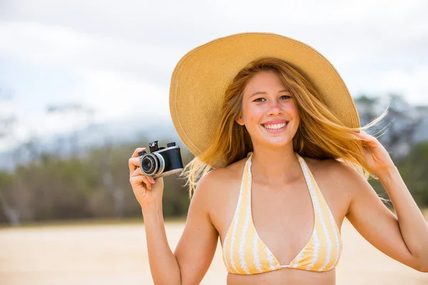 Hermosa mujer en la playa con cámara — Foto de Stock