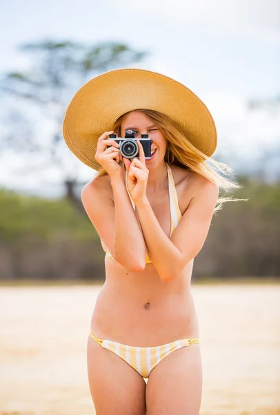 Krásná žena na pláži s fotoaparátem — Stock fotografie