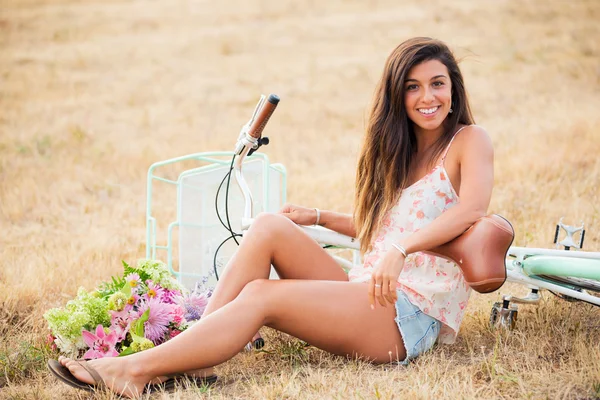 Menina bonita sentada ao lado de bicicleta — Fotografia de Stock