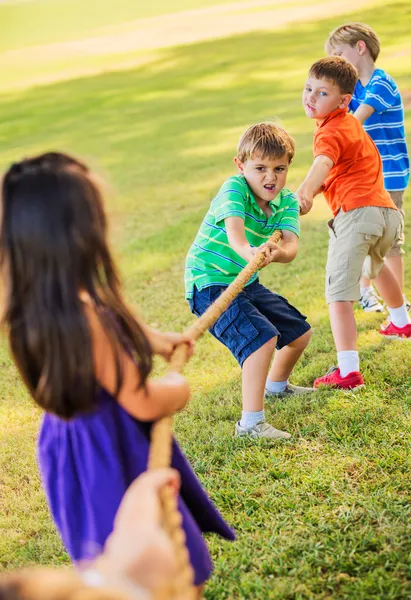 Crianças jogando rebocador de guerra na grama — Fotografia de Stock