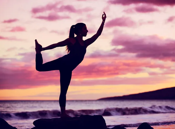 Gün batımında kumsalda yoga yapan kadın. — Stok fotoğraf