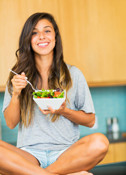 Beautiful young woman eating a bowl of healthy organic salad