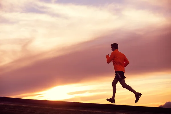 Manliga löpare silhouette, kör in i solnedgången — Stockfoto