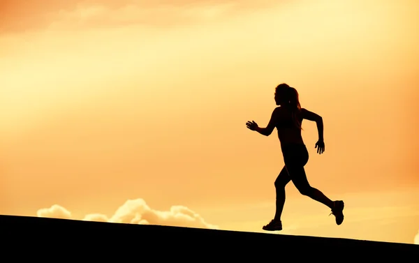 Female runner silhouette, running into sunset — Stock Photo, Image