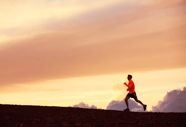 Male runner silhouette, running into sunset — Stock Photo, Image