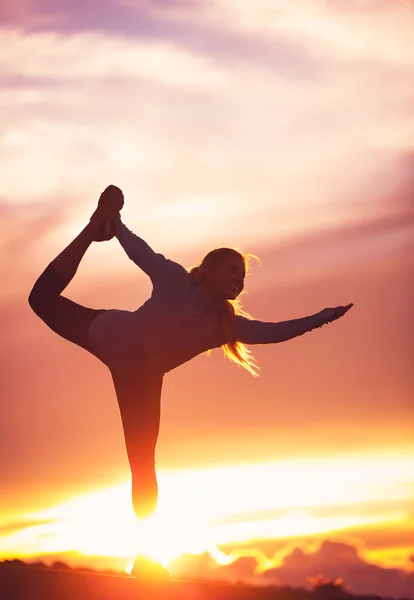 Silueta de una hermosa mujer practicando yoga al atardecer —  Fotos de Stock