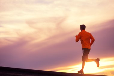 Male runner silhouette, running into sunset clipart