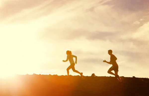 Man and woman runing together into sunset — Stock Photo, Image