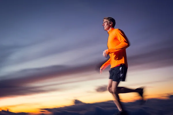 Homem atlético correndo ao pôr do sol crepúsculo com borrão de movimento — Fotografia de Stock