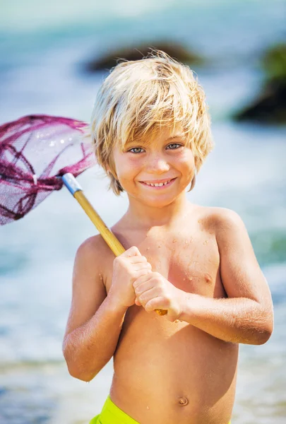 Felice Giovane ragazzo divertirsi in spiaggia, giocando con la pesca ne — Foto Stock