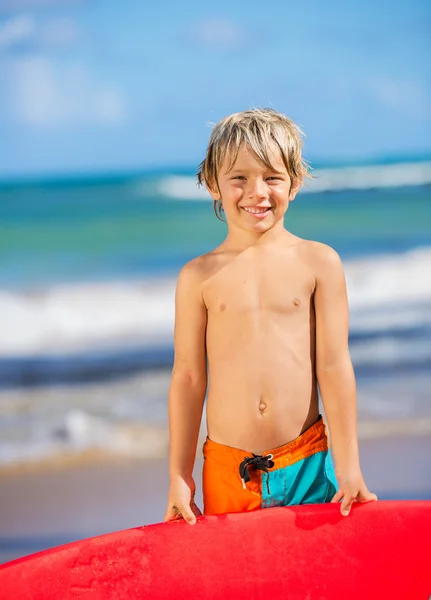 Счастливый мальчик на пляже с доской для серфинга — стоковое фото