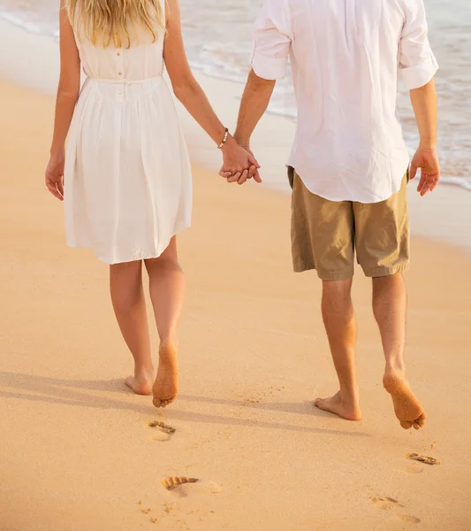 Coppia romantica che si tiene per mano camminando sulla spiaggia al tramonto. L'uomo e — Foto Stock