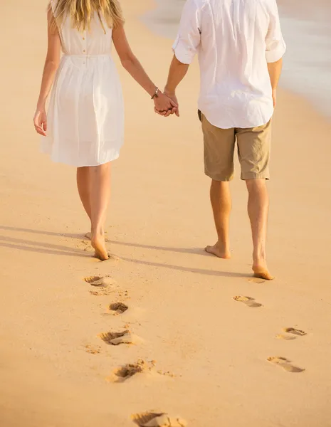 ロマンチックなカップルは夕暮れ時のビーチに歩いて手を繋いでいます。男、 — ストック写真