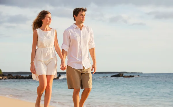 Romantický šťastný pár, chůze po pláži při západu slunce. usmíval se, holdin — Stock fotografie