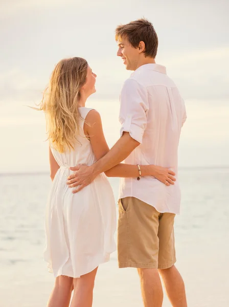 Happy romantic couple on the beach at sunset embracing each othe — Stock Photo, Image
