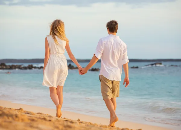 ロマンチックな幸せなカップルの日没でビーチの上を歩いてします。ホールド笑みを浮かべてください。 — ストック写真
