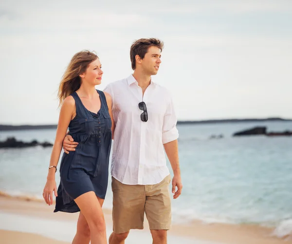 Romántica pareja feliz caminando en la playa al atardecer. Aguantamiento sonriente — Foto de Stock