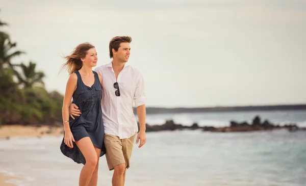 Романтическая счастливая пара, гуляющая по пляжу на закате. Улыбающийся холдин — стоковое фото