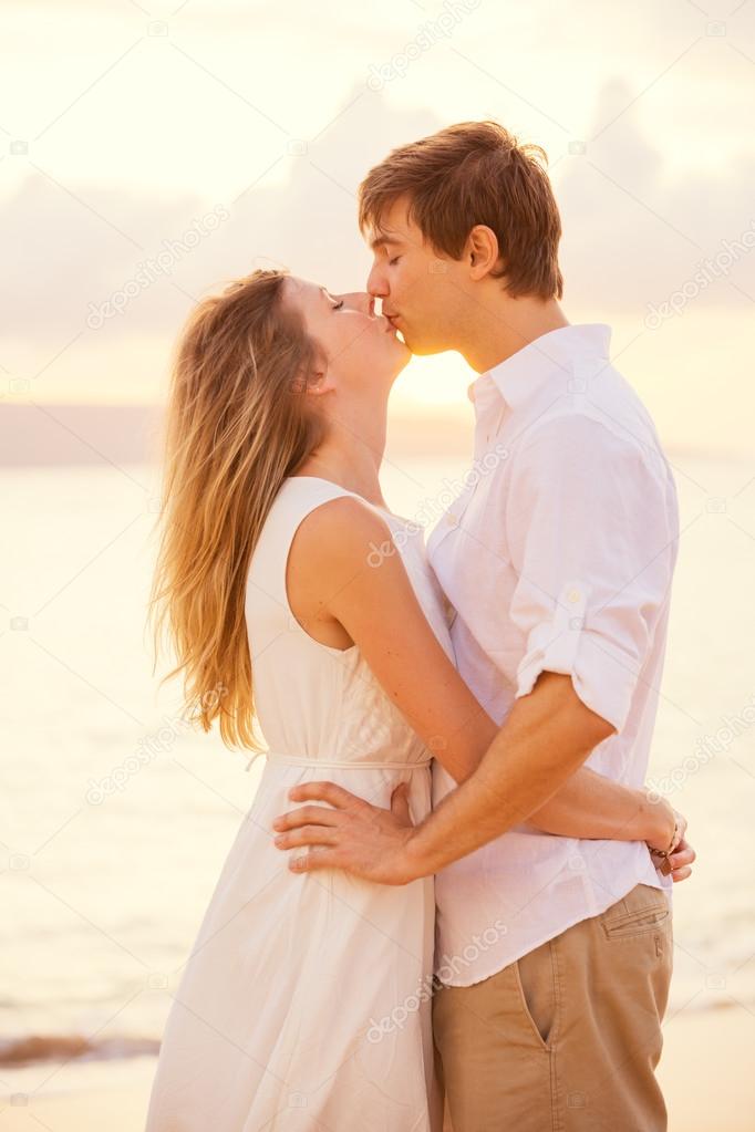 Happy romantic couple kissing on the beach at sunset, Man and wo