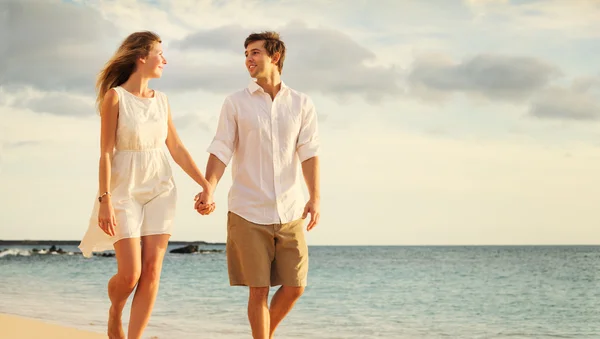 Jovem casal apaixonado andando na praia ao pôr do sol — Fotografia de Stock