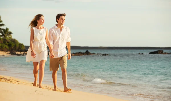 Giovane coppia innamorata che cammina sulla spiaggia al tramonto — Foto Stock