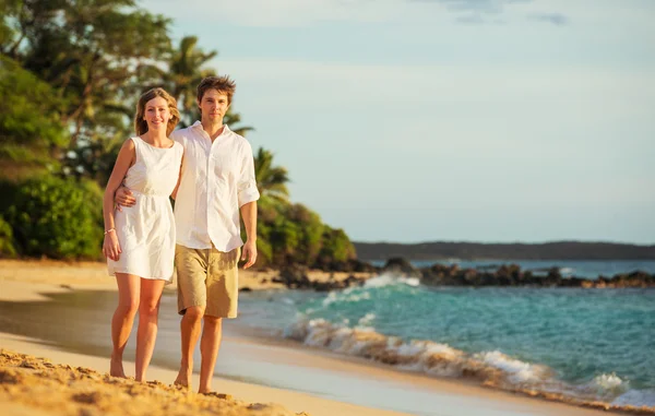 Молодая пара влюблённая прогулка по пляжу на закате — стоковое фото