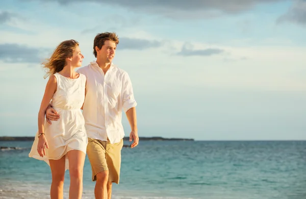 Fiatal pár szerelmes séta a tengerparton naplementekor — Stock Fotó