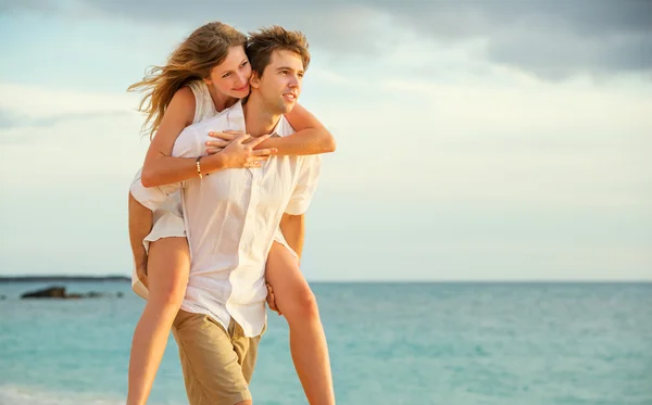 Mladý pár v lásce chůzi na pláži při západu slunce — Stock fotografie
